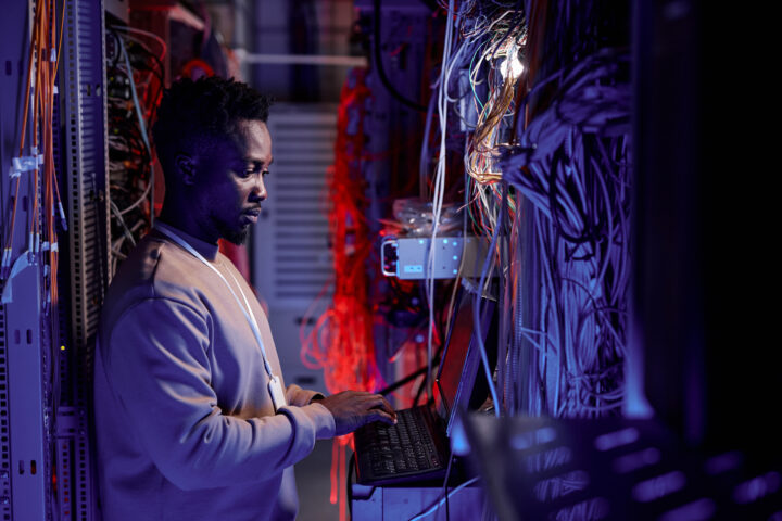 System administrator using computer in server room neon light